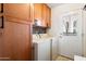 Laundry room featuring a washer, dryer, natural wood cabinets and access to the back yard at 1173 E Beryl Ave, Phoenix, AZ 85020