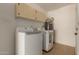 The laundry room has white appliances, tile flooring, and ample overhead storage at 13284 W Aleppo Dr, Sun City West, AZ 85375