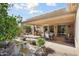 Lush backyard with covered patio, outdoor kitchen, dining area, and decorative pond at 16564 W Wild Horse Way, Surprise, AZ 85387