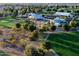 Aerial view of community clubhouse with a swimming pool and a golf course, surrounded by mature trees at 17637 W Browning Dr, Surprise, AZ 85374