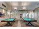 Game room with two pool tables, pendant lighting, and large windows at 17637 W Browning Dr, Surprise, AZ 85374
