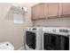 Bright laundry room with washer, dryer, and overhead cabinets for storage at 22499 N Dietz Dr, Maricopa, AZ 85138