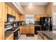 Bright eat-in kitchen features wooden cabinets, granite countertops, black appliances and window over the sink at 2741 N 137Th Ave, Goodyear, AZ 85395