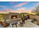 Inviting outdoor patio featuring a stone fireplace and comfortable seating, perfect for enjoying the sunset at 37170 N Greythorn Cir, Carefree, AZ 85377
