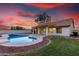 Backyard featuring a pool, covered patio, grass, and desert landscaping under a colorful sunset sky at 3861 S Acacia Ct, Chandler, AZ 85248