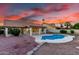 Backyard showcasing a beautiful pool, covered patio, and desert landscaping under a vibrant sunset at 3861 S Acacia Ct, Chandler, AZ 85248