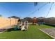 A Gathering-friendly backyard featuring artificial grass, playground equipment, and stylish string lights for outdoor enjoyment at 40467 W Jenna Ln, Maricopa, AZ 85138