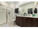 Well-lit bathroom with a double sink vanity and a glass enclosed shower at 40467 W Jenna Ln, Maricopa, AZ 85138