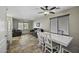 An open-concept living room, with a ceiling fan and a dining area with white table at 40866 W Sanders Way, Maricopa, AZ 85138