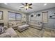 Cozy living room with neutral color scheme, ceiling fan, and large windows for natural light at 40866 W Sanders Way, Maricopa, AZ 85138