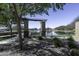 Scenic view of a community pond with a shaded bench and pergola, perfect for relaxation at 40866 W Sanders Way, Maricopa, AZ 85138