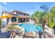 A backyard oasis with a pool, waterfall feature, palm trees, seating, and an outdoor kitchen area for entertaining at 4455 E Palmdale Ln, Gilbert, AZ 85298