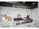 Close up of a stainless steel stovetop with red knobs and a granite backsplash in a modern kitchen at 5455 E Lincoln Dr # 3008, Paradise Valley, AZ 85253