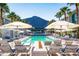 Resort pool area with a fire pit, lounge chairs, umbrellas, and mountain views at 5455 E Lincoln Dr # 3008, Paradise Valley, AZ 85253