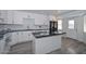 Modern kitchen with white cabinets, black appliances, island, and granite countertops at 6025 W Marconi Ave, Glendale, AZ 85306