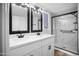 Modern bathroom featuring a double vanity, black fixtures, a bright white countertop, and a glass-enclosed shower at 6201 W Acoma Dr, Glendale, AZ 85306