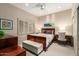 Cozy bedroom with a desk, bench, and patterned accent pillows on a wooden-frame bed at 7380 E Turquoise Ave, Scottsdale, AZ 85258