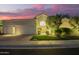Charming home exterior featuring a well-manicured lawn and a three-car garage, illuminated at twilight at 7380 E Turquoise Ave, Scottsdale, AZ 85258