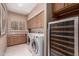Well-appointed laundry room with washer, dryer, built-in cabinets, and wine cooler at 7380 E Turquoise Ave, Scottsdale, AZ 85258