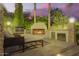 Outdoor kitchen featuring a built-in grill, stainless steel storage, and a cozy stone fireplace at 7380 E Turquoise Ave, Scottsdale, AZ 85258