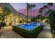 Backyard view of the pool and spa area at dusk, highlighted by soft lighting and mature trees at 7380 E Turquoise Ave, Scottsdale, AZ 85258