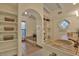 Spa-like bathroom with a tiled soaking tub, arched window, and built-in shelving for storage at 8003 E Sands Dr, Scottsdale, AZ 85255