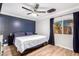 Cozy main bedroom with stylish accent wall, ceiling fan, wood-look floors and a bright window at 11226 W Glenrosa Ave, Phoenix, AZ 85037