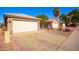 View of the home's two car garage and driveway with neat landscaping and nearby houses at 11226 W Glenrosa Ave, Phoenix, AZ 85037