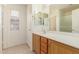 Bright bathroom featuring wood cabinets, double mirrors, and tile flooring at 1268 S 238Th Ln, Buckeye, AZ 85326