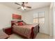 The bedroom includes a window with blinds, a ceiling fan, and a red and brown comforter at 1268 S 238Th Ln, Buckeye, AZ 85326