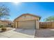 Beige house featuring a large two-car garage, desert landscaping, and a concrete driveway under a bright blue sky at 1268 S 238Th Ln, Buckeye, AZ 85326