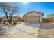 Beige house featuring a large two-car garage, desert landscaping, and a concrete driveway under a bright blue sky at 1268 S 238Th Ln, Buckeye, AZ 85326