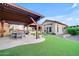 An outdoor dining and seating area, featuring a covered patio, lush green lawn, and neutral desert landscape at 1708 W Gambit Trl, Phoenix, AZ 85085