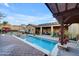 View of the pool and patio area, complete with outdoor furniture, pergola, and mature landscaping at 1708 W Gambit Trl, Phoenix, AZ 85085