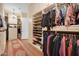 Spacious walk-in closet featuring custom shelving, hanging racks, carpet runner, and ample storage for clothes and accessories at 1708 W Gambit Trl, Phoenix, AZ 85085