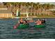 People enjoy canoes on a lake, with palm trees and boat docks in the background at 17960 W Long Lake Rd, Goodyear, AZ 85338