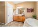 Bathroom featuring double sink vanity, soaking tub with tiled surround, and decorative lighting at 23024 N De La Guerra Ct, Sun City West, AZ 85375