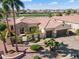 Impressive aerial view of a home with a stone facade, tile roof, mature palm trees, and easy golf course access at 23024 N De La Guerra Ct, Sun City West, AZ 85375