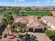 Stunning aerial of home with meticulously maintained landscaping, red tiled roof, and serene golf course backdrop at 23024 N De La Guerra Ct, Sun City West, AZ 85375