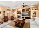 Cozy living room with a ceiling fan, fireplace, and a large built-in entertainment center at 23024 N De La Guerra Ct, Sun City West, AZ 85375