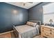 Serene bedroom with navy blue walls, a wood frame bed, and a matching nightstand and lamp at 25634 W Samantha Way, Buckeye, AZ 85326