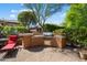 This backyard features an outdoor grill area, red lounge chairs, and mature plants at 26293 W Runion Ln, Buckeye, AZ 85396