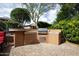 Close up of the built-in outdoor kitchen with BBQ and counter surrounded by mature trees at 26293 W Runion Ln, Buckeye, AZ 85396