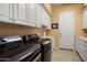 This laundry room features modern appliances, a sink, white cabinets, and tile floors at 26293 W Runion Ln, Buckeye, AZ 85396