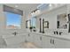 Bright, modern bathroom with a soaking tub, dual sinks, white cabinets, and a window view at 5812 E Sanford St, Mesa, AZ 85215