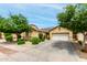 Inviting single-story home with a two-car garage, desert landscaping, and a well-kept front yard with mature trees at 10414 W Windsor Ave, Avondale, AZ 85392