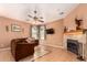 Cozy living room with a fireplace, ceiling fan, and neutral tile flooring at 10414 W Windsor Ave, Avondale, AZ 85392