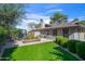 Manicured backyard featuring mature trees, green lawn, brick planter with colorful flowers and greenery, and gray brick home exterior at 14821 N Hana Maui Dr, Phoenix, AZ 85022
