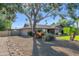 Charming single story home with gravel yard, mature trees, green lawn, palm trees, gated driveway, and gray brick exterior at 14821 N Hana Maui Dr, Phoenix, AZ 85022