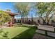 Spacious backyard featuring artificial grass, patio, dining set, fire pit, and mature trees at 1513 W Mitchell Dr, Phoenix, AZ 85015